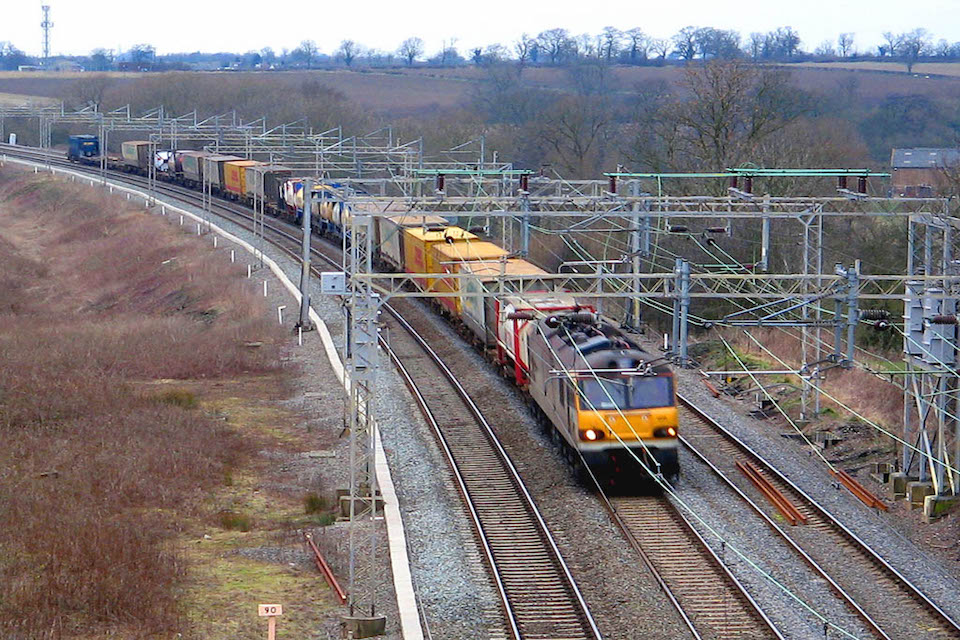 Diesel freight train under the wires on the West Coast Main Line