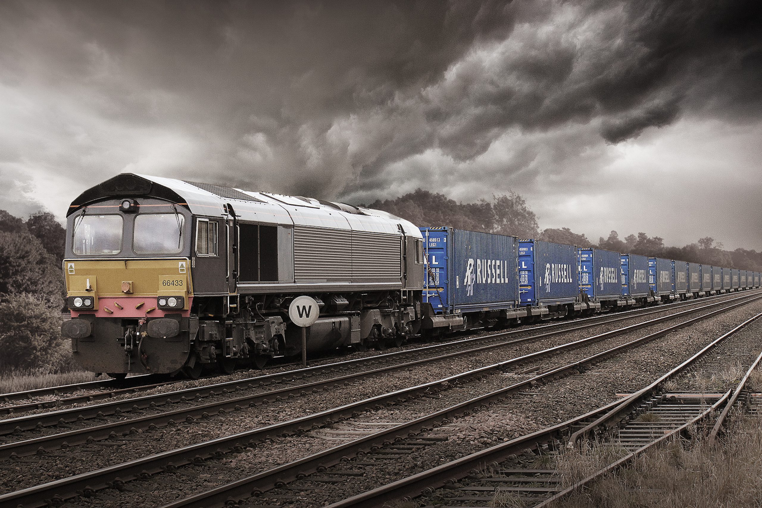 Class 66 locomotive hauling a train of Russell containers under a leaden sky