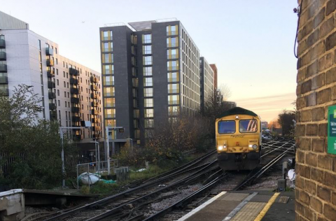 A freight train passes between tower blocks in London