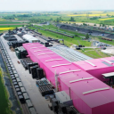 Large pink warehouses with rai connection in a green field setting