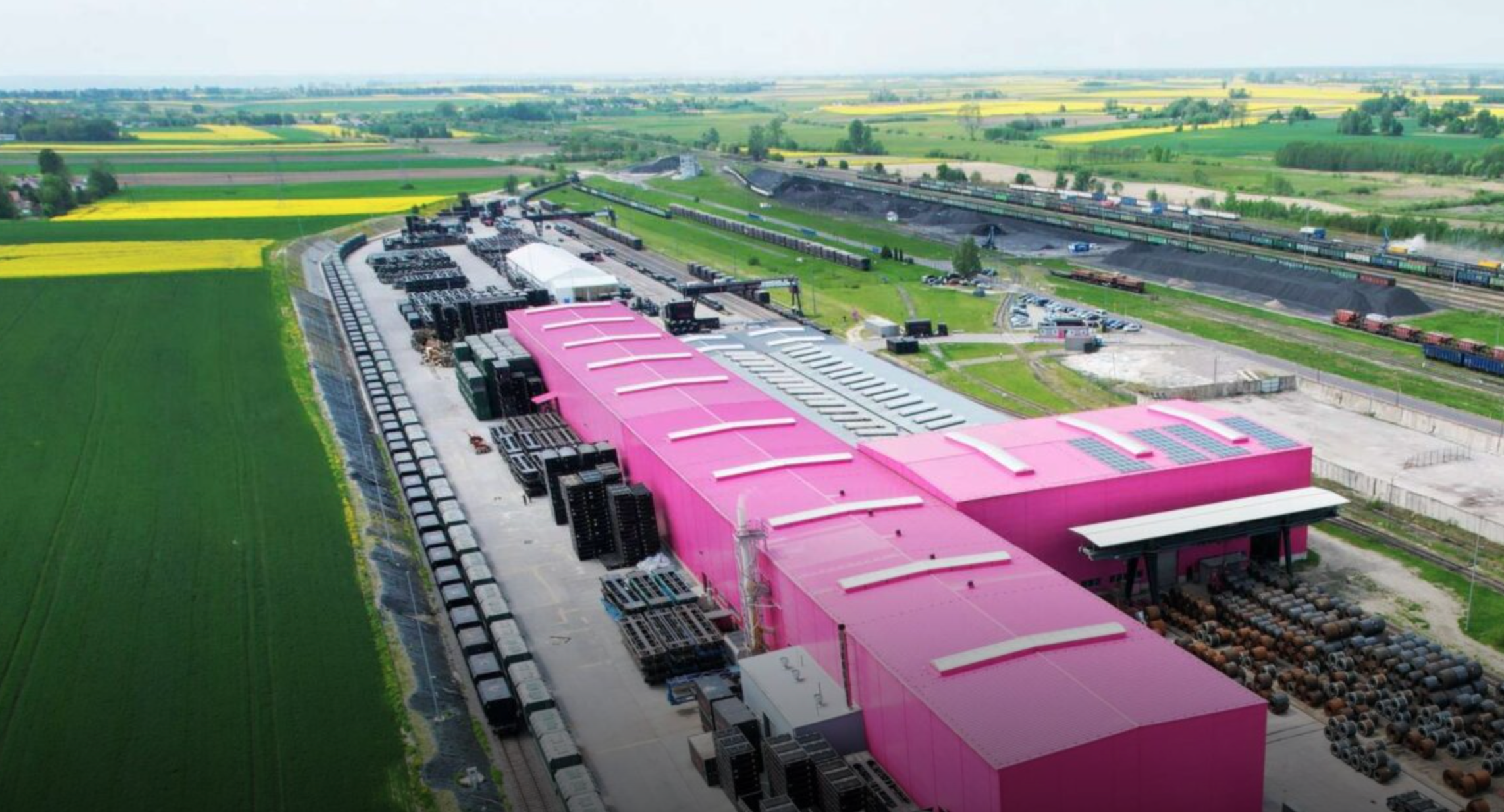 Large pink warehouses with rail connection in a green field setting
