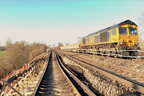 Freight train approaching camera on open tack with blue sky