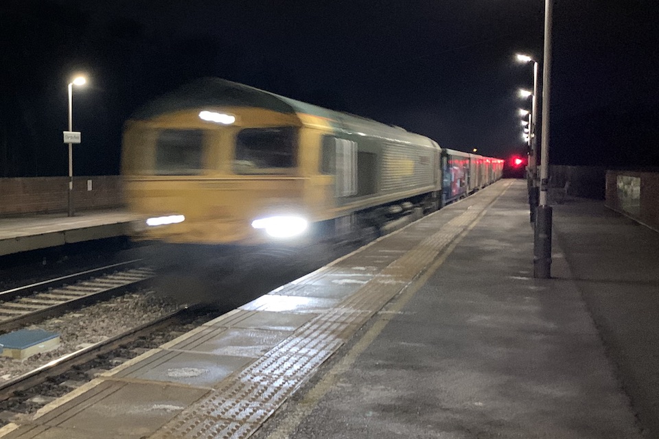 Freight train speeds through a station at night