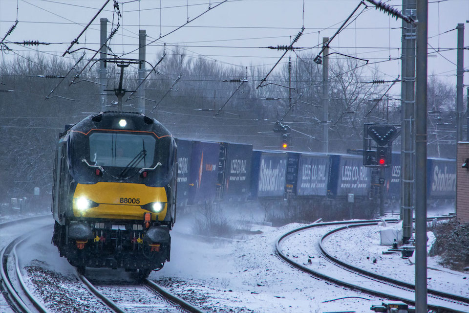 A class 88 belonging to Direct Rail Services at speed in the snow hauling a container train