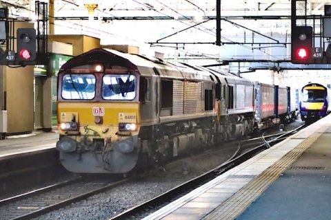 Freight and passenger trains pass each other at Edinburgh Waverley station