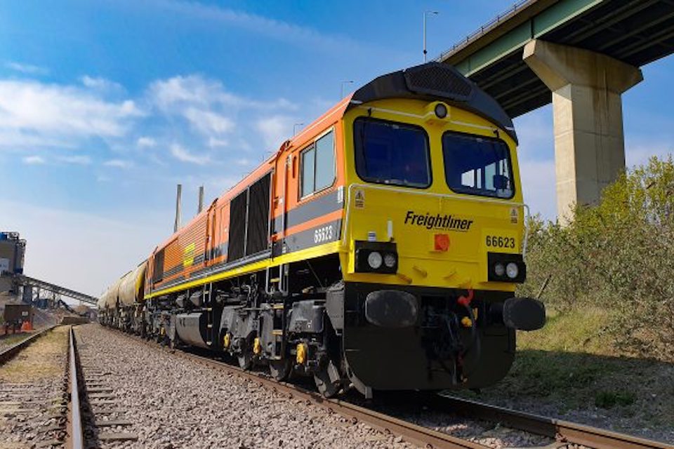 Three quarter ground level view of a class 66 locomotive in Freightliner gold and black livery