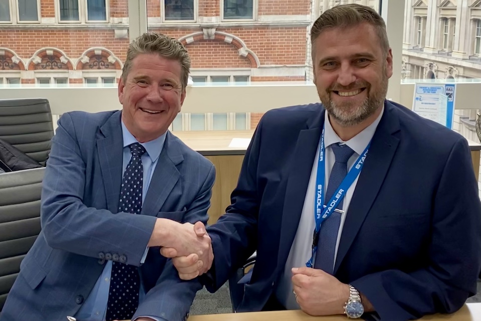 Two businessmen shaking hands and smiling for the camera. One is JoJohn Smith, CEO of GB Railfreight, and the other is Paul Patrick, Managing Director of Stadler Rail Service UK.