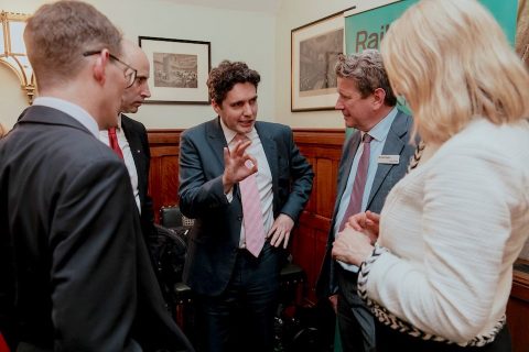 Four businessmen and one business woman standing talking, in the centre is the UK Rail Minister Huw Merriman and the CEO of GB Railfreight, John Smith