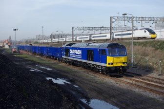 Freight train carrying bulk ballast running alongside a Pendolino on the West Coast Main Line in London