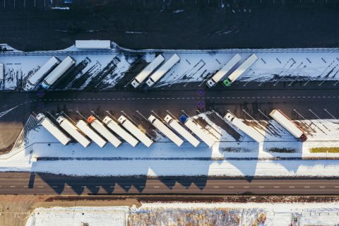 Trucks lined up diagonally on lorry park viewed from above