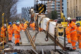 Engineers in orange suits with crane laying track