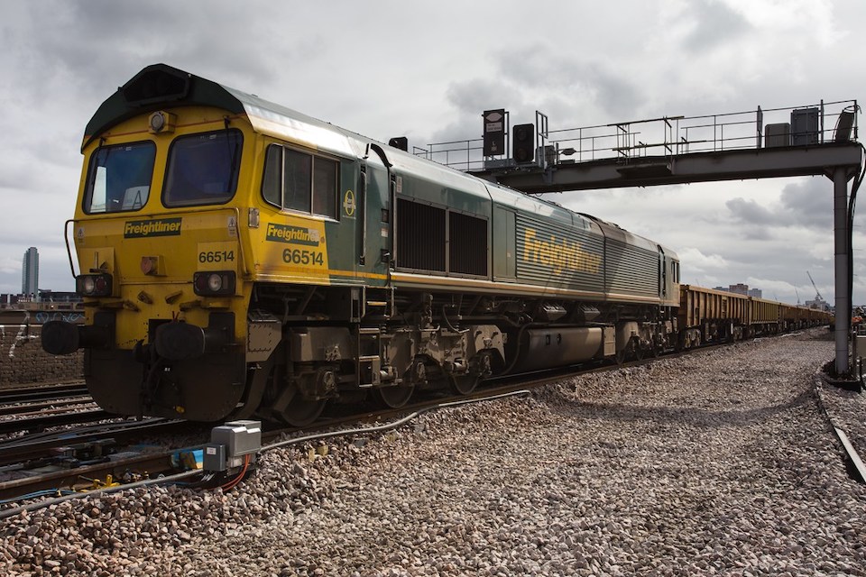 three quarters shot from ground level of a Freightliner class 66 hauling an aggregates train