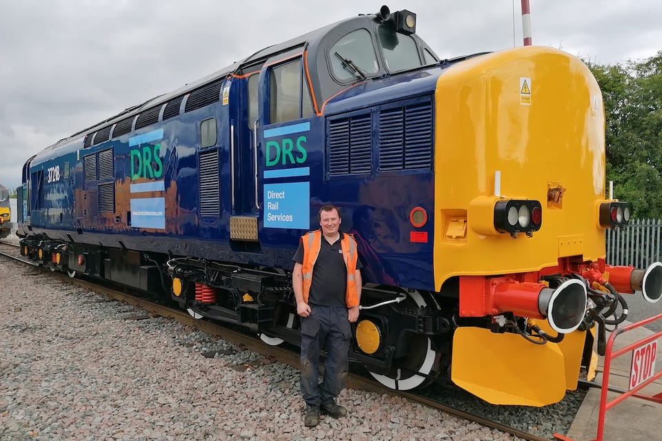DRS employee posing in front of a class 37 locomotive in pristine condition