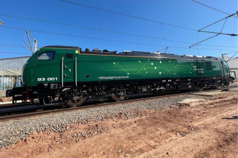 Class 93 tri-mode locomotive in green livery for Rail Operations Group standing on barren ground in Spain, ready for delivery to UK