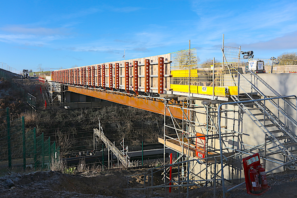 Bridge deck under construction showing main steel span bridging over railway in deep cutting below