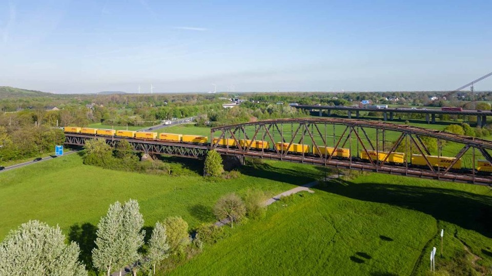 DB operated train of DHL continuers on a bridge in the countryside