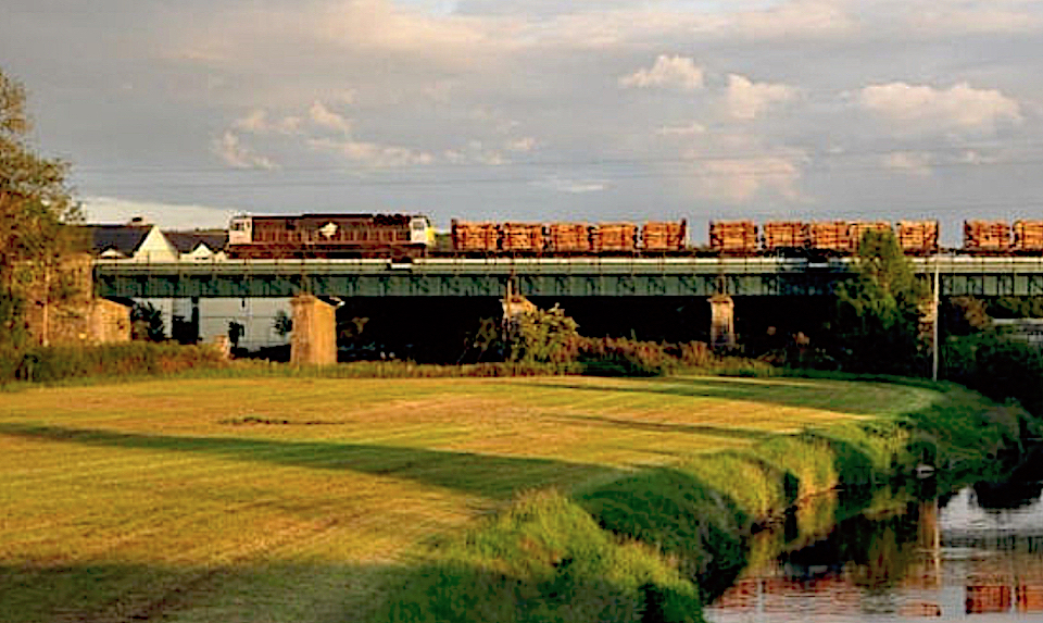Ireland bulk freight train crossing a low viaduct over farmland