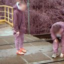 Two children stand on a level crossing placing ballast stones on track