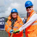 Scottish Transport Minister Fiona Hyslop and Scotland's Railway Managing Director Alex Haynes pose holding the lever to insert a golden clip into the Levenmouth Railway, a commemorative sign is unfurled behind them