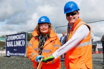 Scottish Transport Minister Fiona Hyslop and Scotland's Railway Managing Director Alex Haynes pose holding the lever to insert a golden clip into the Levenmouth Railway, a commemorative sign is unfurled behind them