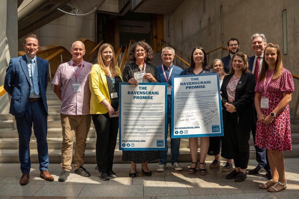Campaigners and politicians pose for a photo outside the Scottish Parliament in Edinburgh holding large scale versions of the Ravenscraig Promise document