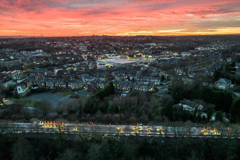 Sunrise over Huddersfield with rail engineers at work in foreground