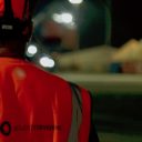Night time at rail yard in Southampton with a close cup of the back of a Solvet Stevedores operative showing the logo of the Compnay on the back of his High viability vest