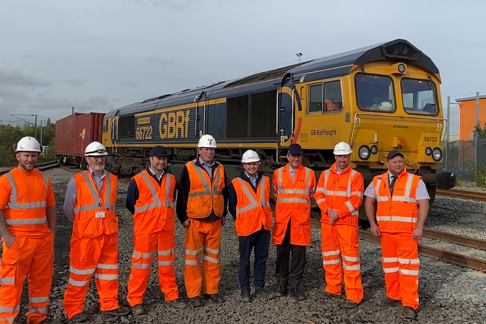 Picture of several engineers in orange suits standing in front of a class 66 locomotive