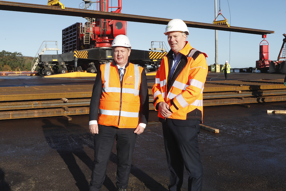Two businessmen in orange hive vests and hard hats standing in front of a load of railway track. They are Iarnród Éireann CEO, Jim Meade with Pat Keating, CEO of Shannon Foynes Port Company