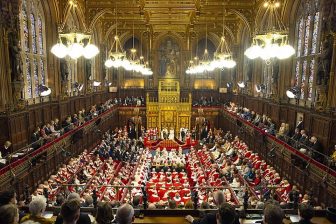 Wide shot of the House of Lords with the King and Queen in attendance for the State opening of Parliament. Full of lords in regal dress