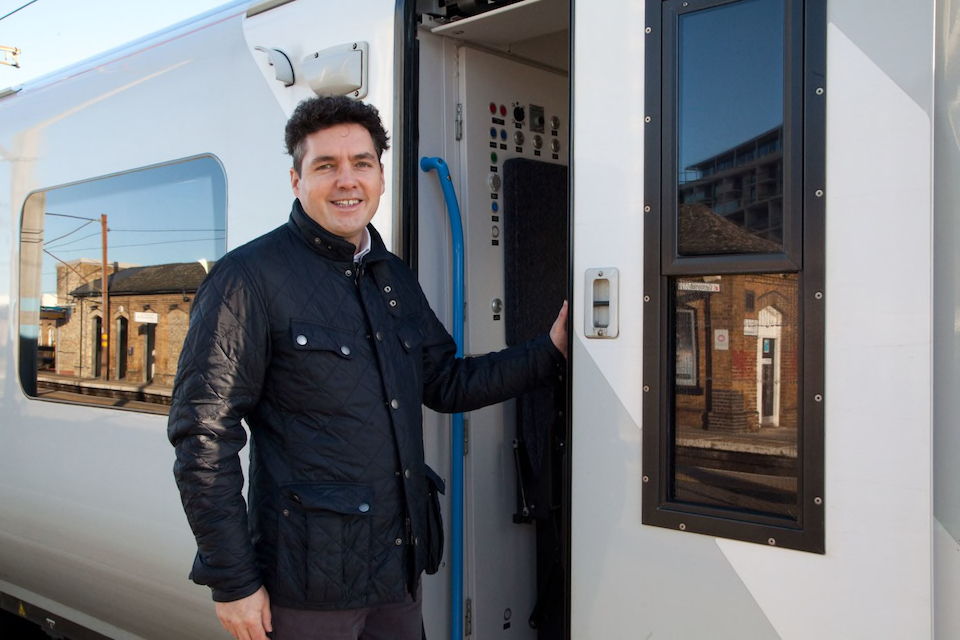 Leather clad rail minister Huw Merriman smiles as he boards a train